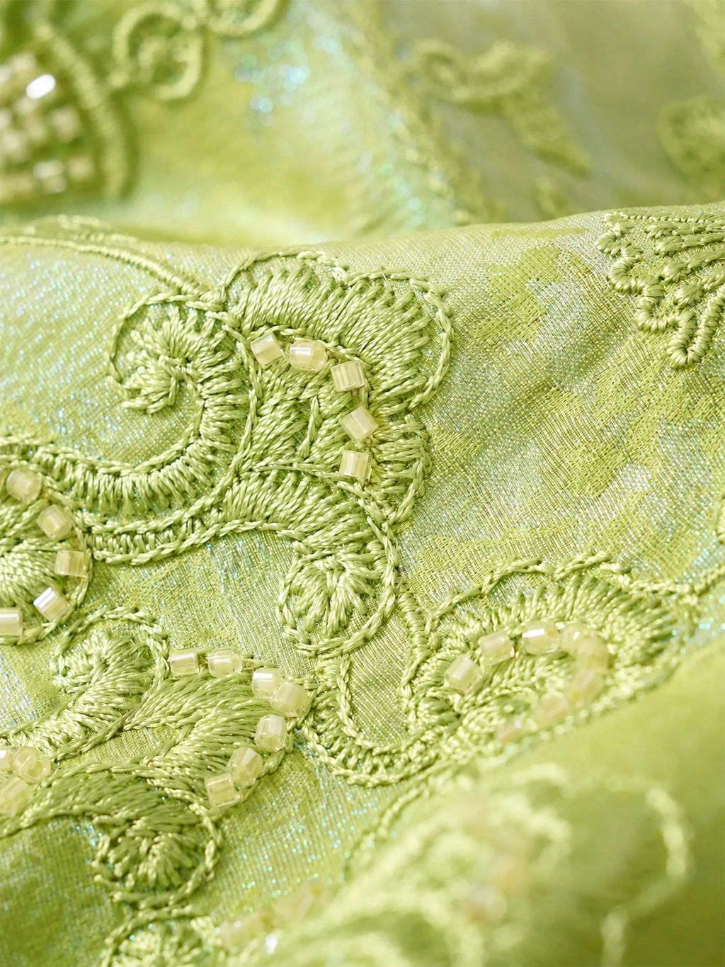 Detailed view of handcrafted embroidery on a celadon green mulberry silk blouse.
