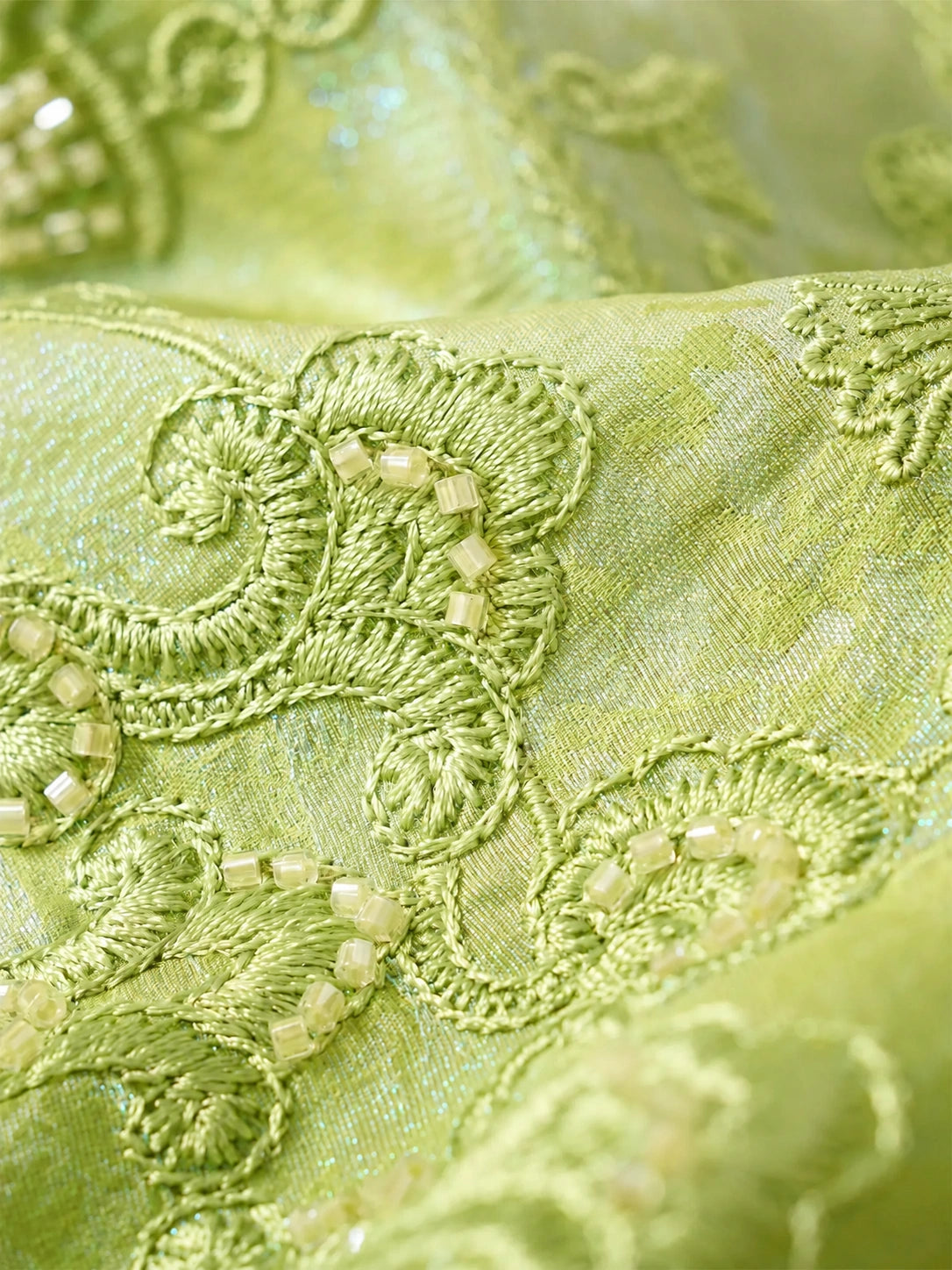 Detailed view of handcrafted embroidery on a celadon green mulberry silk blouse.