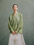 Woman wearing a celadon green embroidered mulberry silk blouse with a Mandarin collar by Gambiered Silk.
