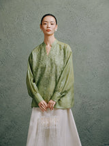 Woman wearing a celadon green embroidered mulberry silk blouse with a Mandarin collar by Gambiered Silk.