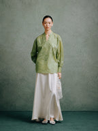 Full-length view of a woman styling a celadon green embroidered silk blouse with a flowing white skirt.