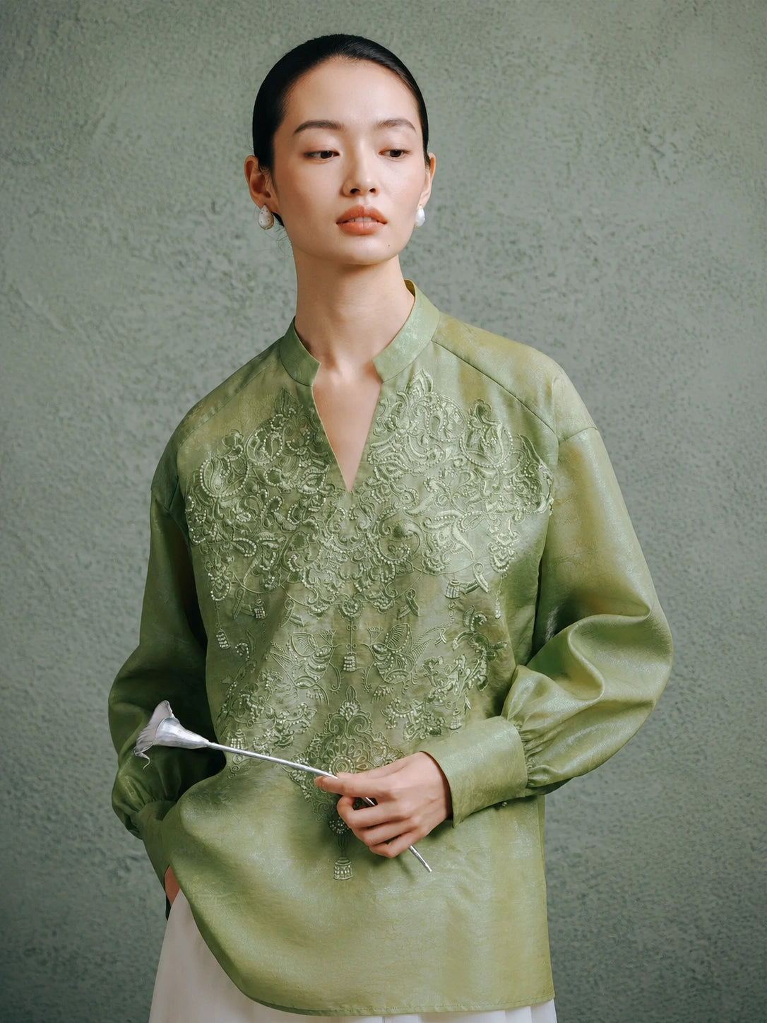 Close-up of a celadon green mulberry silk blouse featuring intricate embroidery and a Mandarin collar.