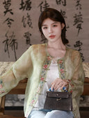 Model styling a Chinese-inspired embroidered silk overshirt with a structured handbag