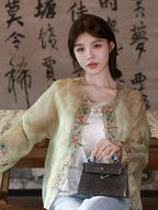 Model styling a Chinese-inspired embroidered silk overshirt with a structured handbag