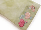Detail of the embroidered floral cuff and tonal texture on a sage green silk overshirt