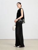 Model wearing a black embroidered silk velvet vest with a sheer hem and wide-leg trousers.