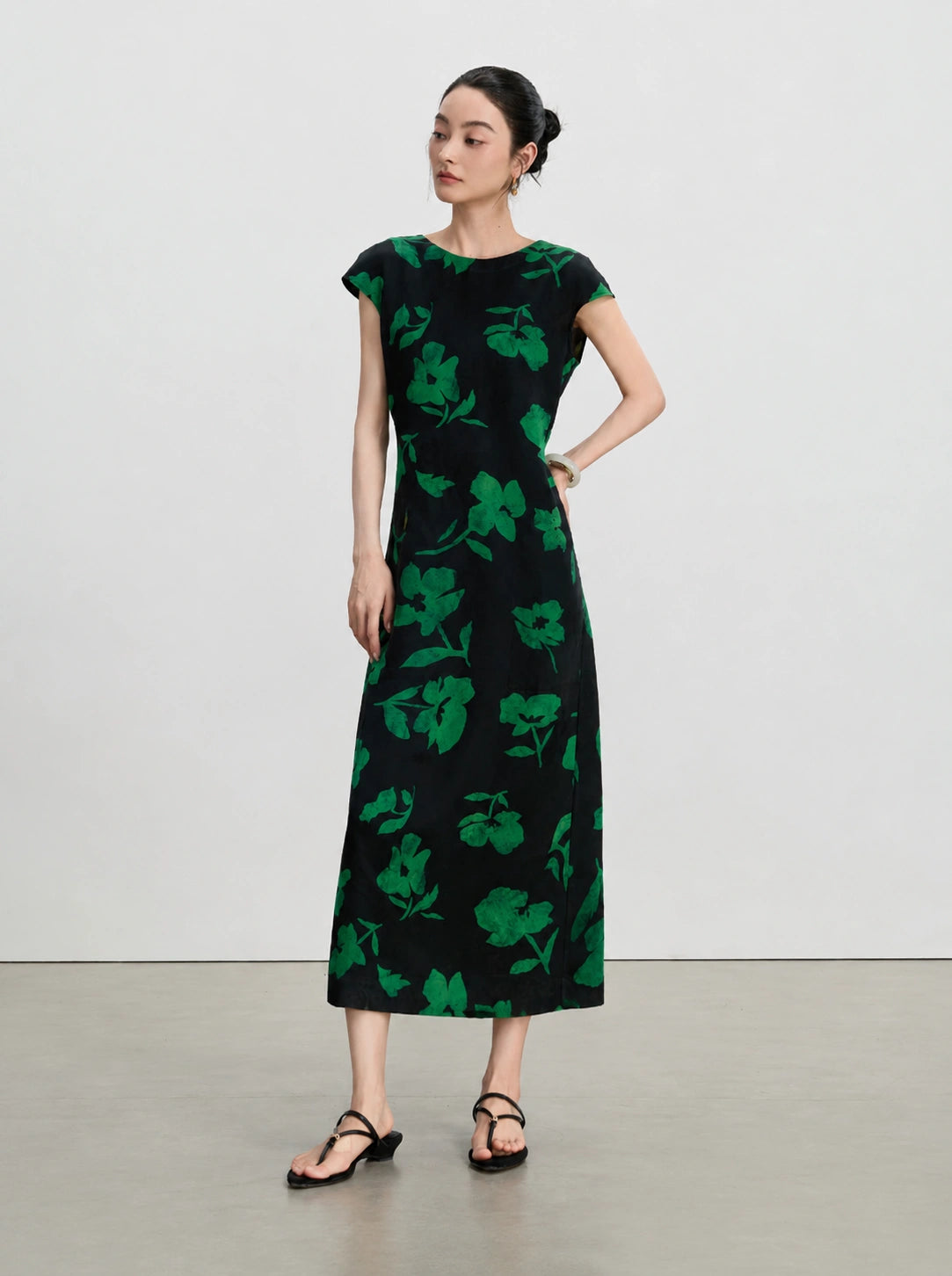 Full front view of an emerald floral gambiered silk A-line dress with a round neckline.