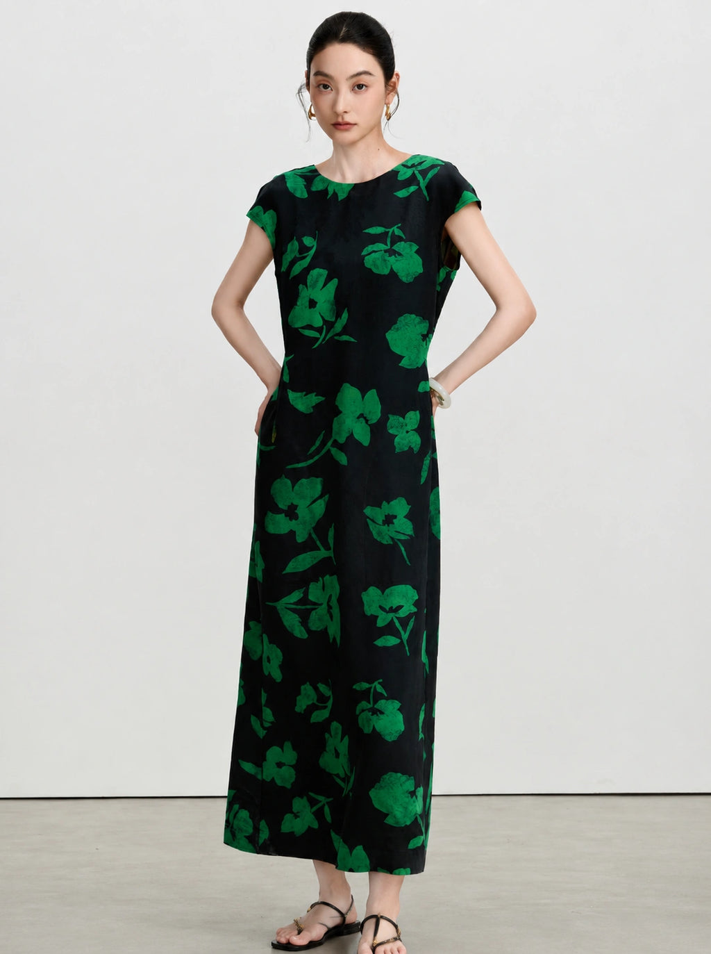 Woman wearing a black and emerald green floral A-line silk maxi dress.