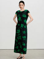Woman wearing a black and emerald green floral A-line silk maxi dress.
