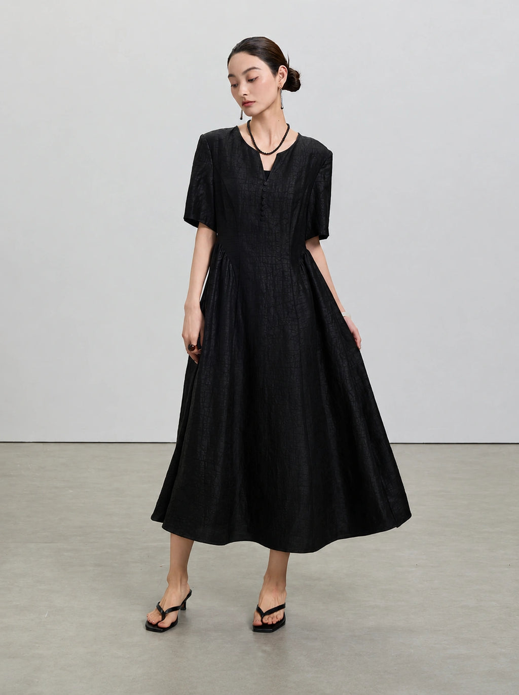 Full-length view showing the fitted bodice and flowing gathered skirt of the black silk dress