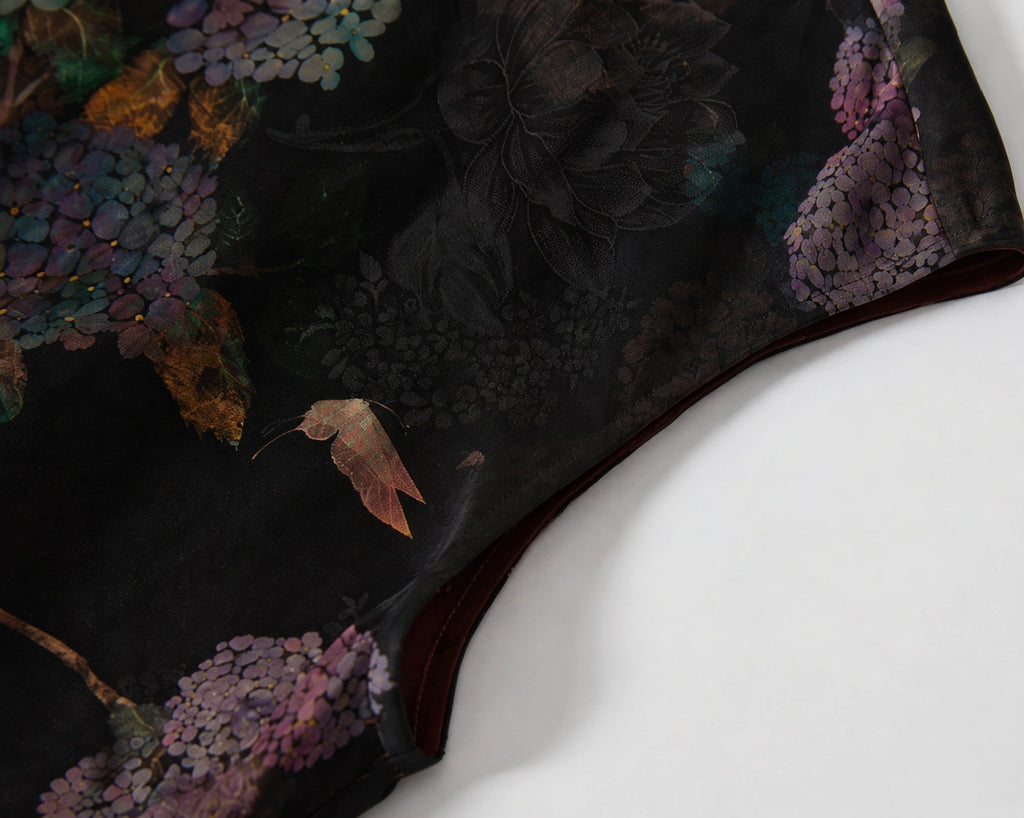 Close-up of the cap sleeve and purple hydrangea pattern on black silk fabric.