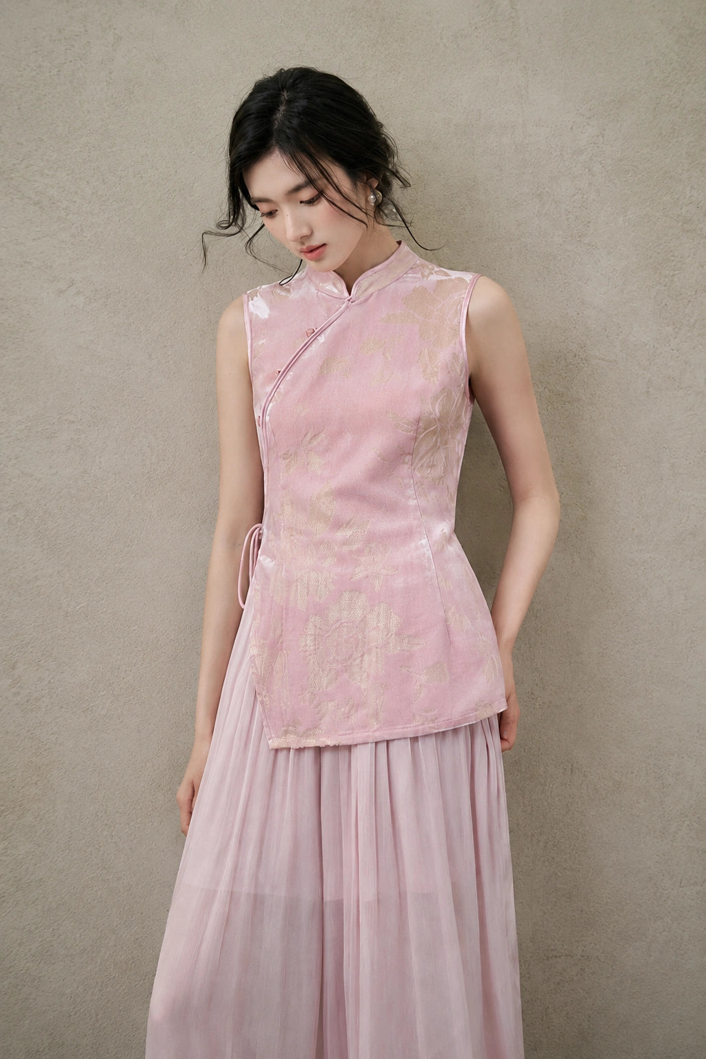 Three-quarter view of a blush-pink floral cut-velvet vest styled with lightweight wide-leg trousers