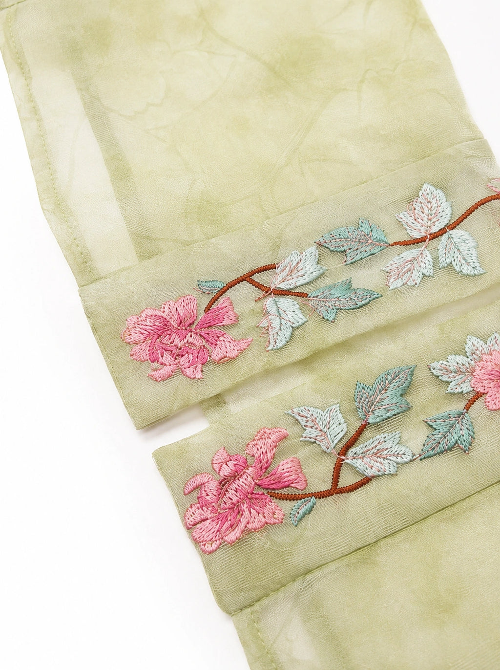 Close-up of floral embroidery on the cuff of a sage green silk overshirt
