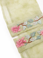 Close-up of floral embroidery on the cuff of a sage green silk overshirt