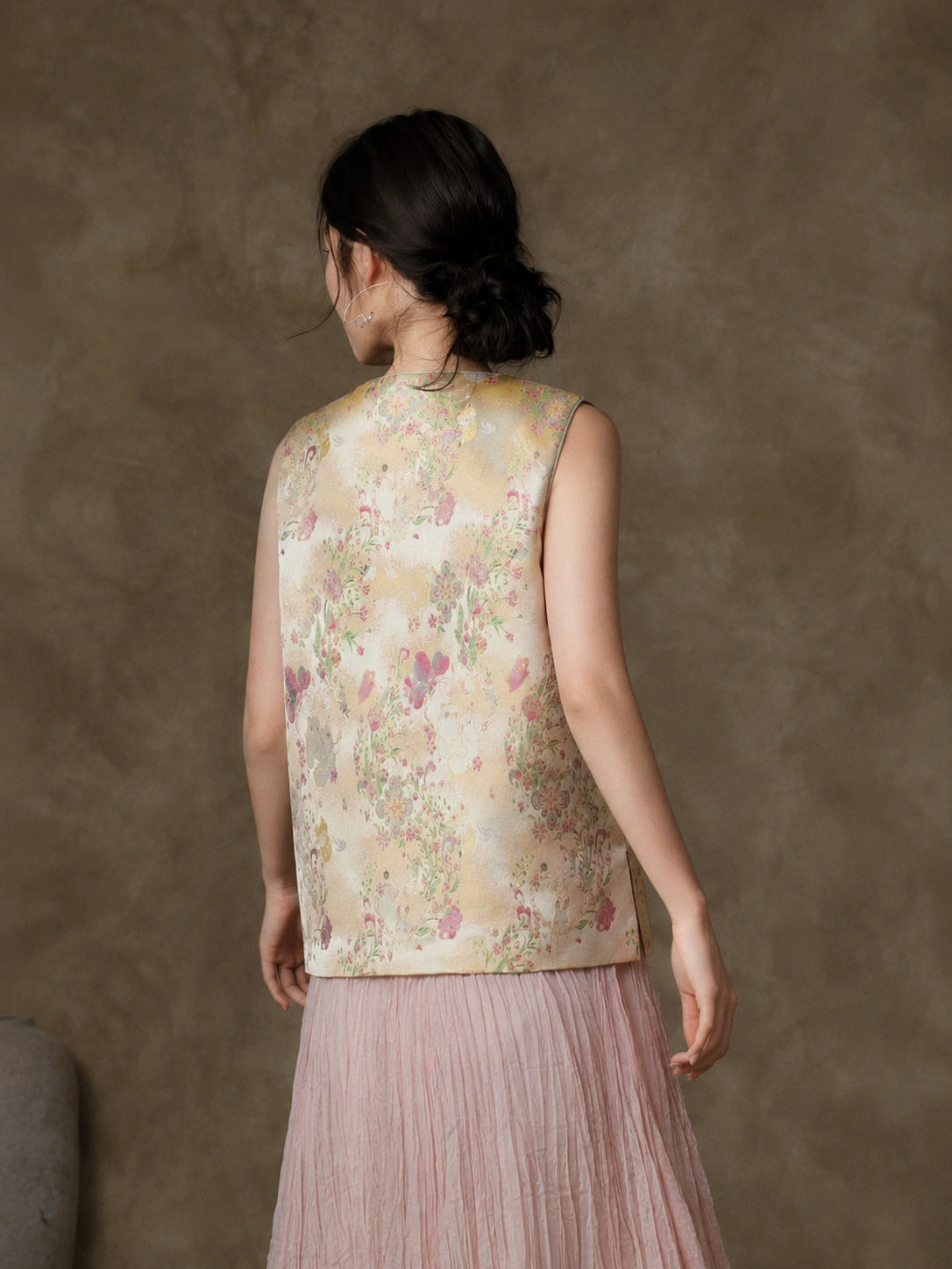 Back view of the sleeveless champagne jacquard vest with pink and green garden motifs