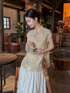 Lifestyle photo of a woman wearing the Warm Sand floral Chinese style sleeveless top in a traditional teahouse by Gambiered Silk.
