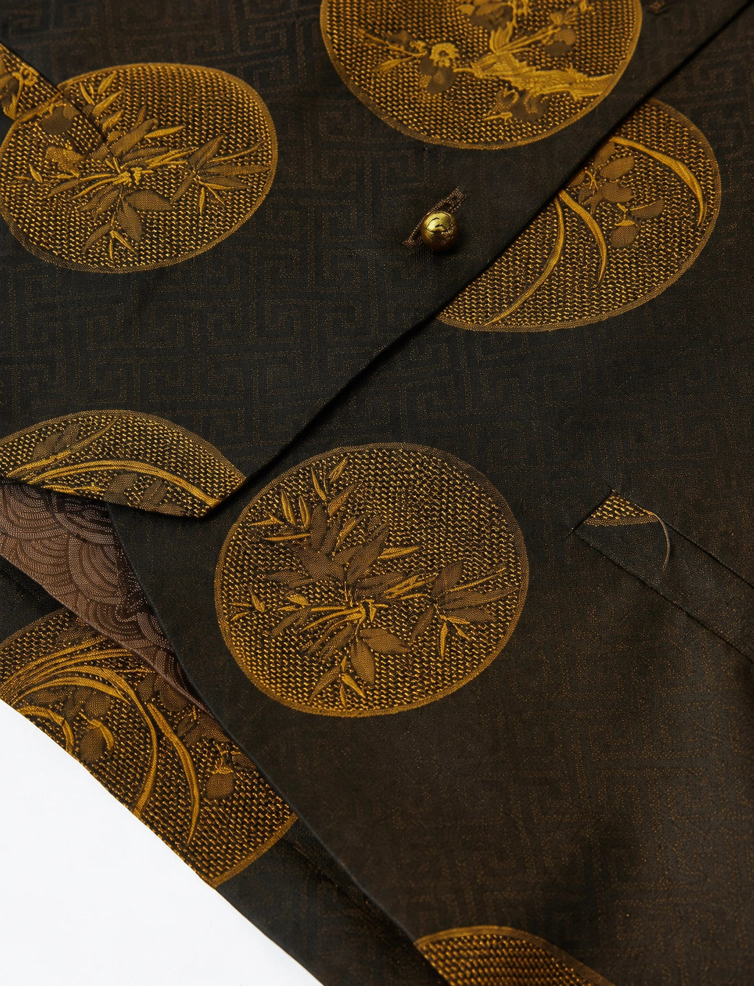 Close-up of the botanical medallion pattern, gold-tone button closure and welt pocket on the Chinese-style vest.