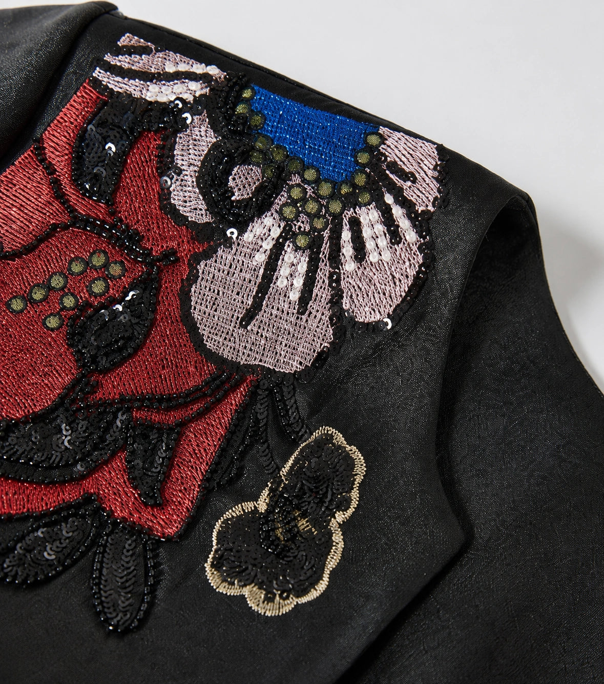 Detailed view of the red, pink, blue and black floral embroidery with sequins and bead accents