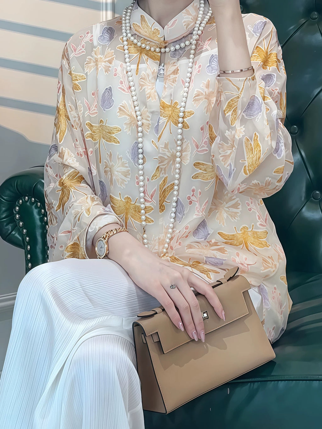 Close-up of a model wearing a floral silk-blend blouse with layered pearl necklaces
