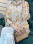 Close-up of a model wearing a floral silk-blend blouse with layered pearl necklaces