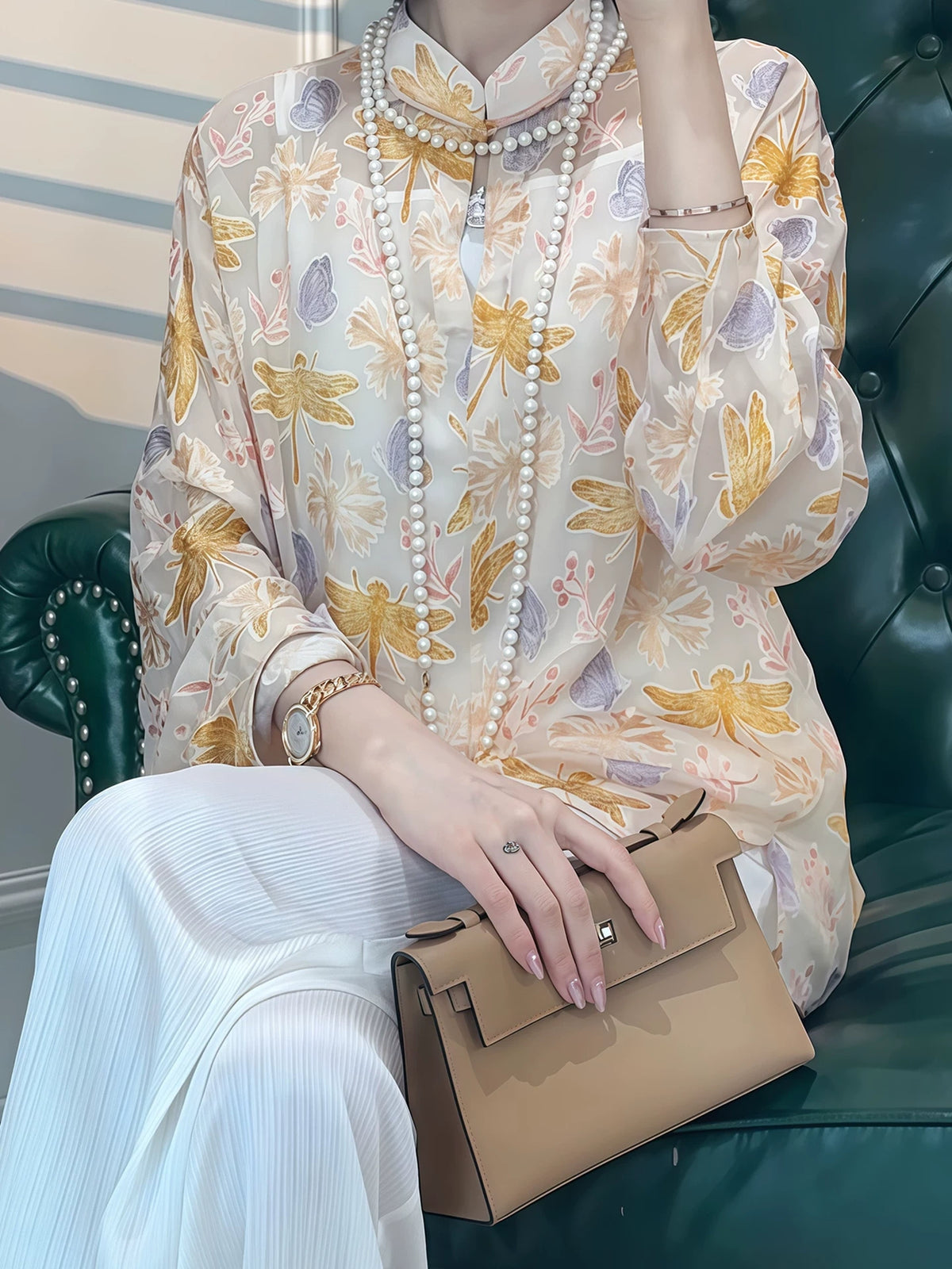 Close-up of a model wearing a floral silk-blend blouse with layered pearl necklaces