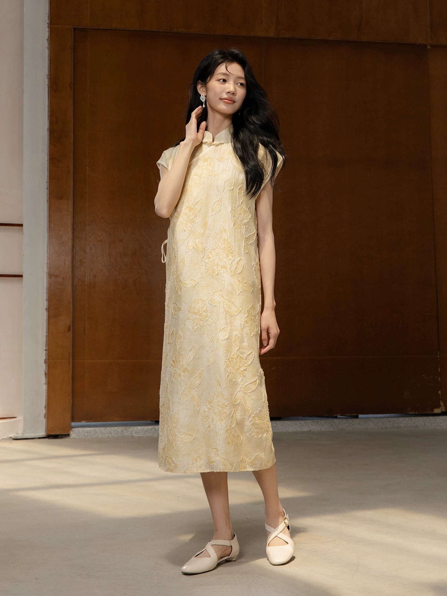 Woman wearing a floral textured summer midi dress in a modern architectural setting