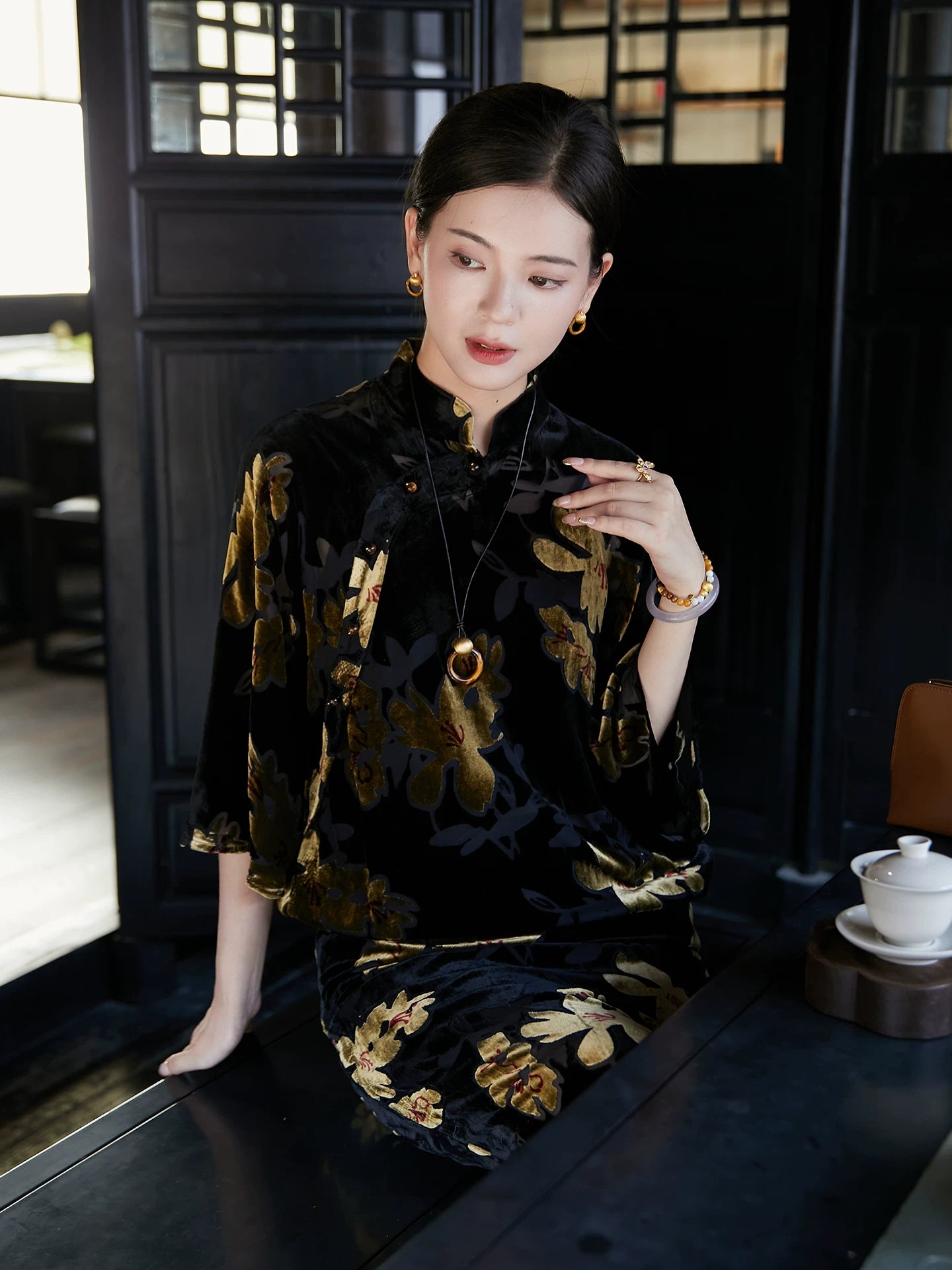 Woman wearing a floral velvet Mandarin collar midi dress in an elegant tea house setting