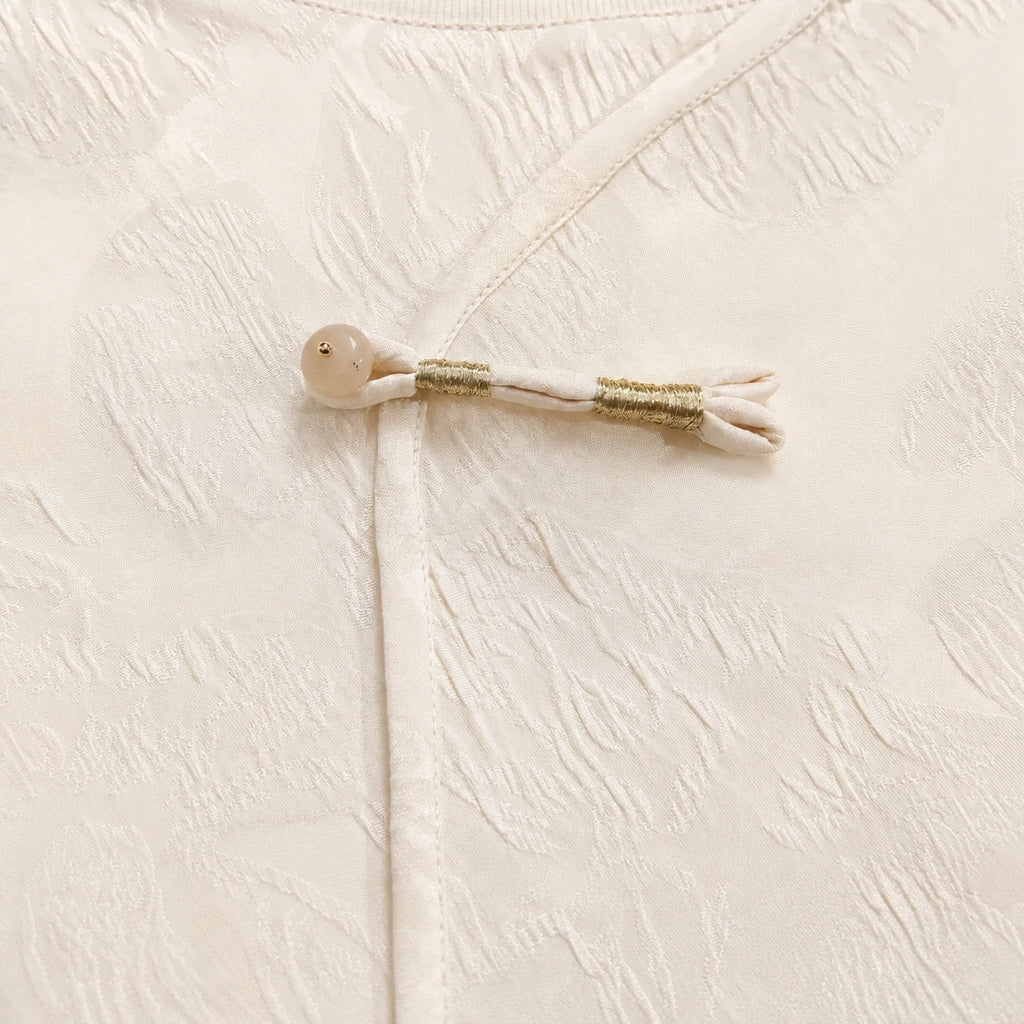 Detailed view of the decorative frog closure with gold thread and a round button