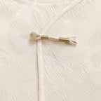 Detailed view of the decorative frog closure with gold thread and a round button