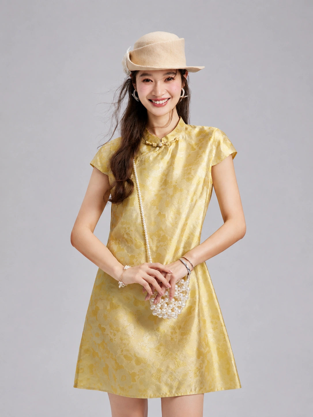 Model wearing a luminous golden Fuguang Jin silk dress with tonal botanical motifs.