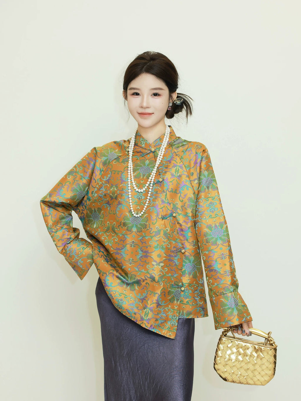 Model wearing a gold and jade green patterned reversible silk jacket with a diagonal front closure