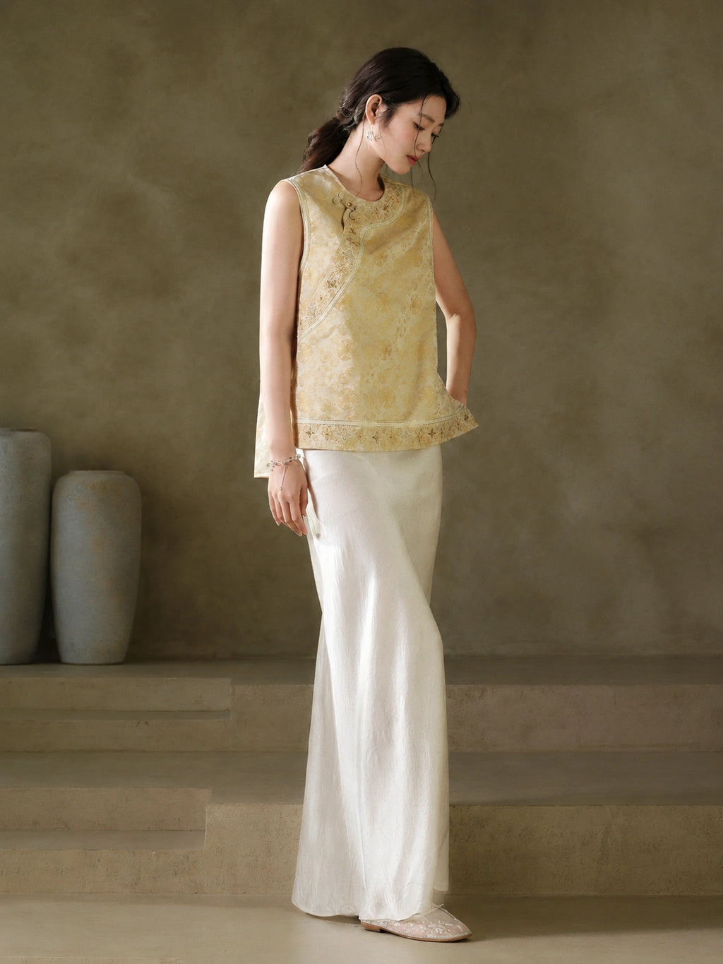 Three-quarter view of the gold jacquard vest showing its embroidered neckline and hem border
