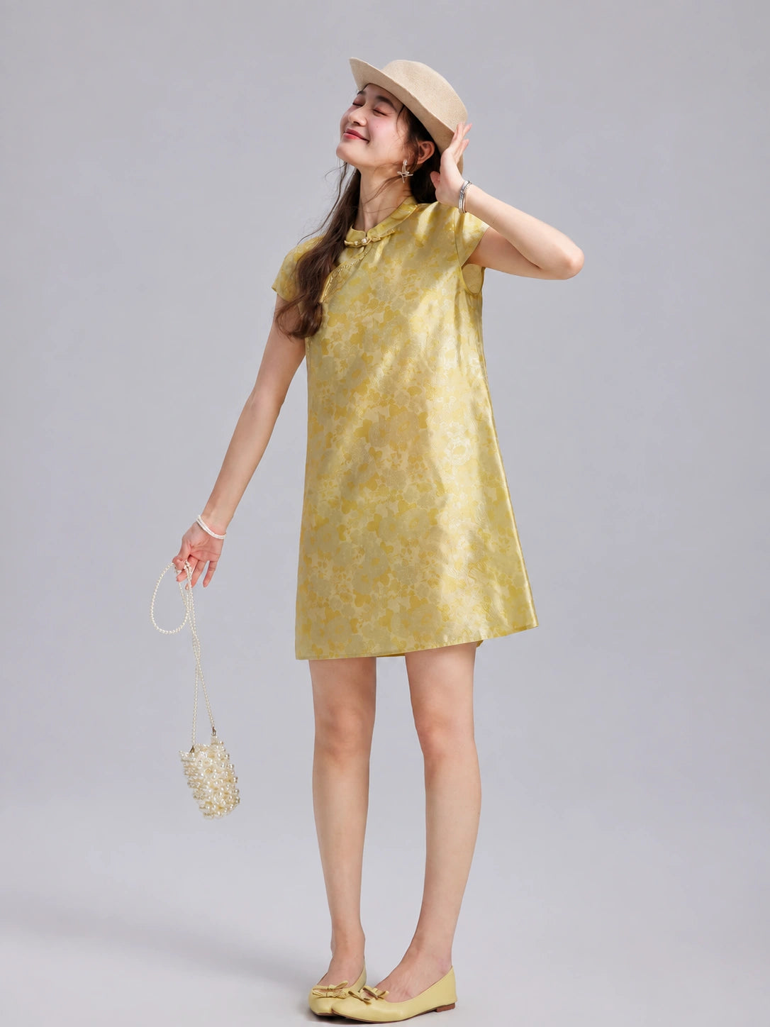 Model wearing a champagne-gold silk shift dress with short sleeves and a Mandarin collar.