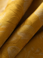 Close-up of lustrous golden mulberry silk fabric with tonal woven butterfly and floral motifs