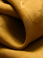 Close-up of lustrous antique-gold mulberry silk jacquard with tonal butterfly and botanical motifs.