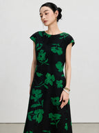Three-quarter view of a New Chinese black silk dress with bold emerald botanical flowers.