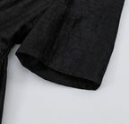 Close-up of the elbow-length sleeve and subtle crackled texture of black Hei Gui Xiangyunsha silk