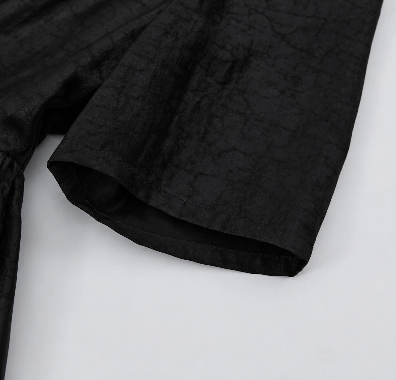 Close-up of the elbow-length sleeve and subtle crackled texture of black Hei Gui Xiangyunsha silk