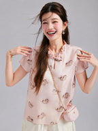 Model wearing a Gambiered Silk blush silk top with scattered pony motifs and a dimensional ruffle collar