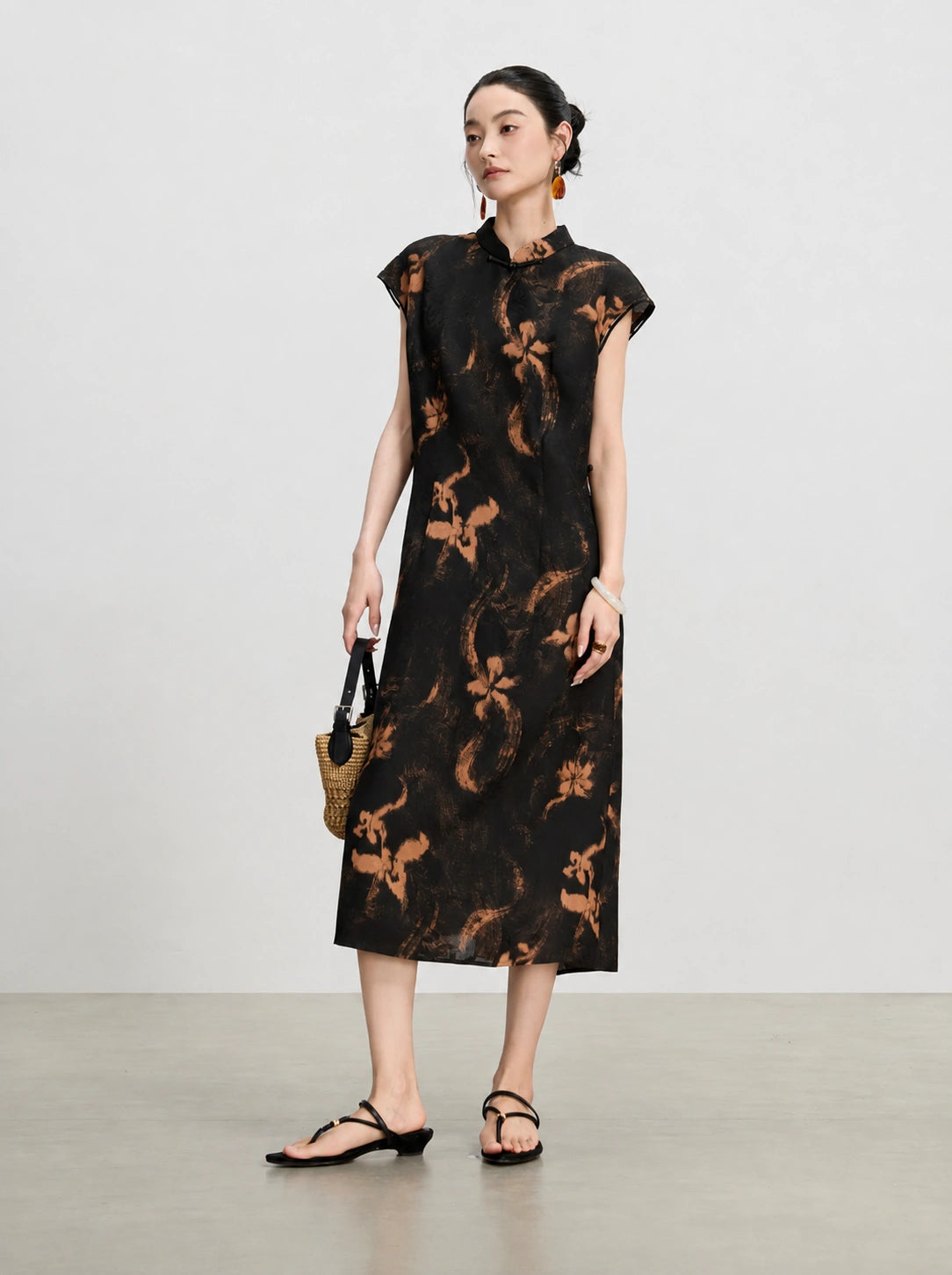 Three-quarter view of a sleeveless black Hua Luo silk midi dress with copper floral print