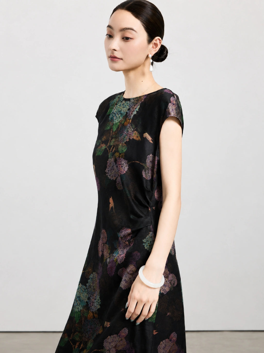 Side view of a black floral silk dress with cap sleeves and gathered waist detail.