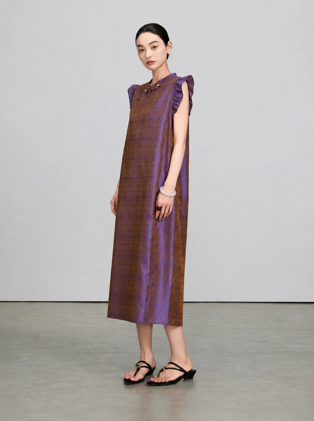 Front three-quarter view of an iridescent purple and bronze mulberry silk qipao dress with flutter sleeves.