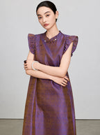 Portrait view of a woman wearing an iridescent purple and bronze New Chinese silk dress.