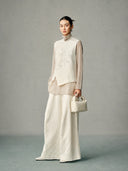 Model wearing an ivory wool-silk vest with tonal beaded bamboo leaves, stand collar and asymmetric front