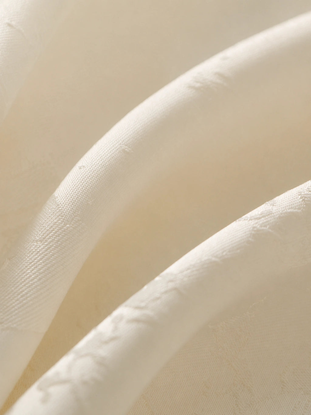 Close-up of warm-ivory polyester satin woven with subtle tonal butterfly jacquard.