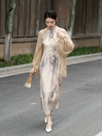 Model wearing an ivory ink print silk cheongsam with a lightweight silk shawl while walking outdoors.