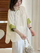 Close-up of the ivory silk top with green contrast cuffs and subtle floral texture
