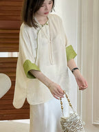 Close-up of the ivory silk top with green contrast cuffs and subtle floral texture