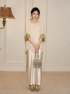 Model wearing a relaxed ivory silk top with green cuffs and a flowing white skirt