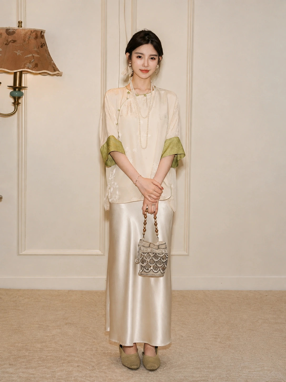 Model wearing a relaxed ivory silk top with green cuffs and a flowing white skirt